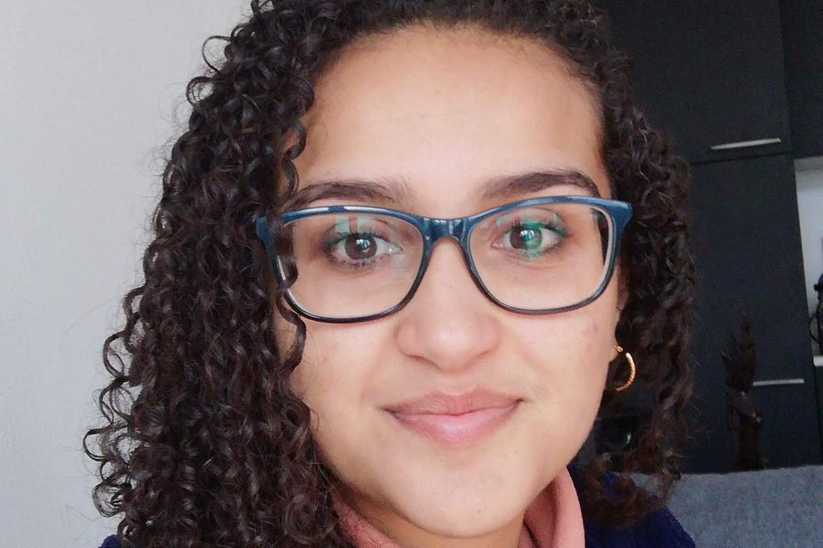 Suhaliah in a blue jumper smiling with glasses 